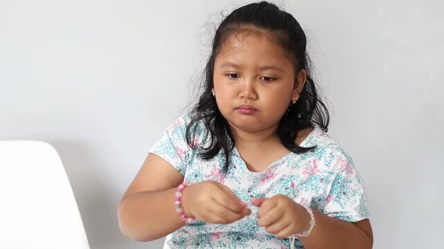 young Asian girl shelling and eating boiled peanuts in a room at home