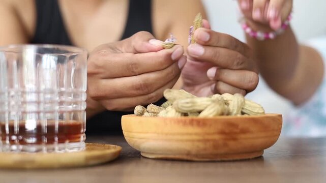 A man's hand peeling peanuts with his daughter, Healthy eating