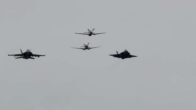 Four military aircraft flying in formation during heritage flight show against overcast sky.