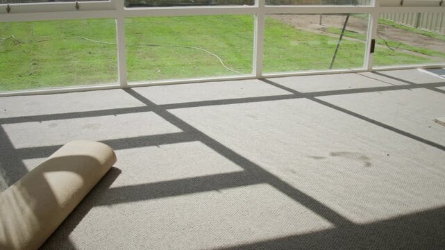 Sunlit interior of a mid-to-late 20th century Australian suburban home,
featuring a dated carpeted sunroom with large windows casting geometric shadows across the floor.