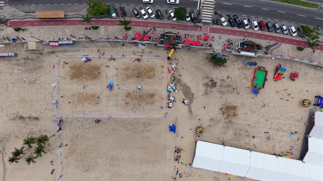 Praia do Anil beach sports courts and promenade with volleyball nets and beach activity in Angra dos Reis, aerial top down backdrop