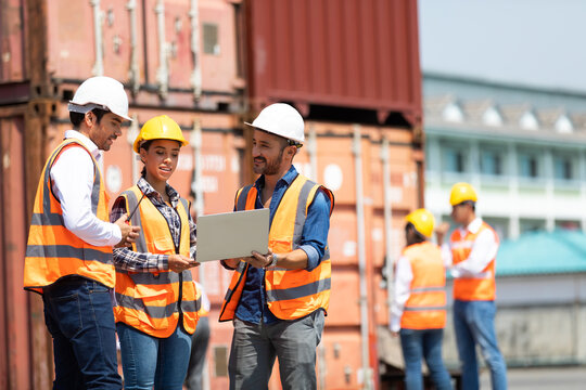 Hispanic man harbor worker talking on the walkie-talkie radio and control loading containers at container warehouse. container yard port of import and export goods