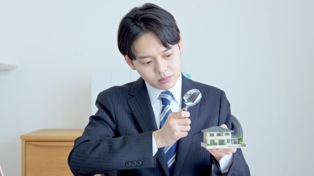 家を虫眼鏡で見る男性