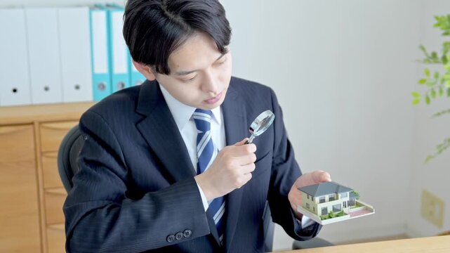 家を虫眼鏡で見る男性
