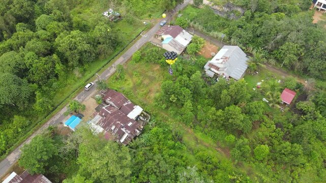 Drone aerial rural village with balloon cluster over green forest