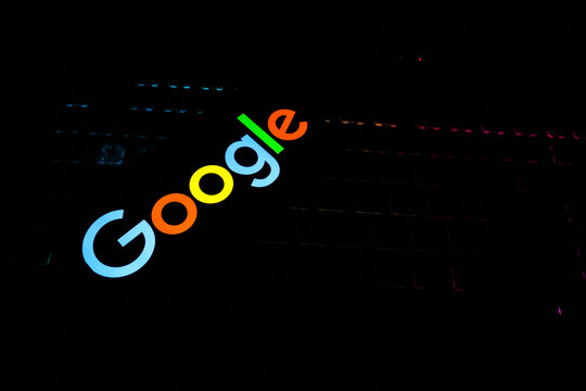 Vibrant Multicolored Google Logo Glowing Against a Dark Backlit Mechanical Gaming Keyboard Background - Concept for Modern Search Engine Tech, Digital Marketing, and Online Innovation
