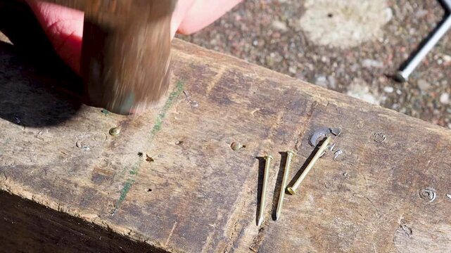 Video of hammering a nail into a wooden beam.