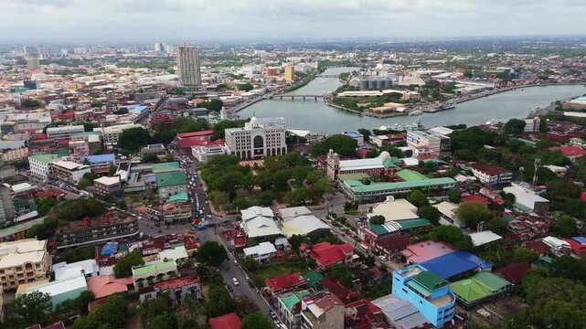 drone fly above downtown Iloilo City, Panay Island, Philippines revealing church and river urban cityscape