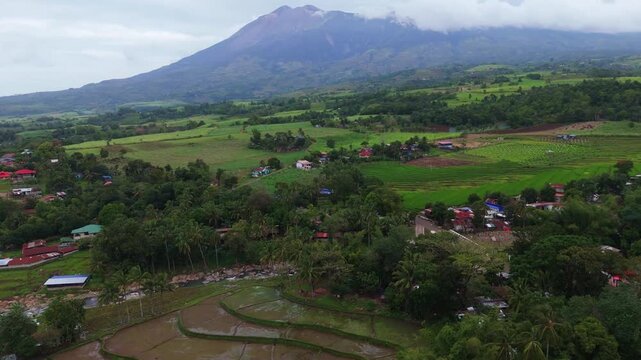 Aerial view of lush green rice terraces and tropical landscape in Canlaon City, Negros Oriental. Scenic rural countryside of the Philippines featuring mountains under a cloudy sky