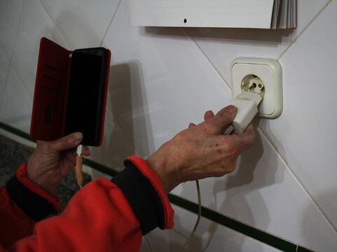 Cargar tel&eacute;fono m&oacute;vil con bater&iacute;a baja con cargador de pared conectando clavija a enchufe