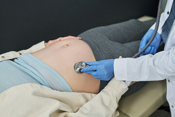 Close up of pregnant woman receiving prenatal examination while doctor monitoring fetal health with...
