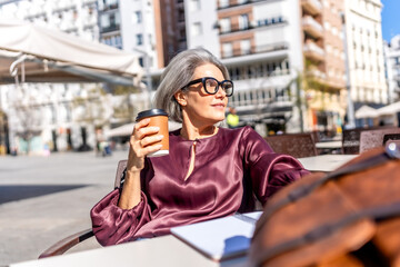 Fototapeta premium Elegant woman enjoying coffee at outdoor urban cafe