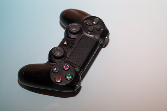 Lviv, Ukraine - March 19, 2026: A black DualShock 4 wireless controller is positioned at an angle on a light blue-and-white gradient background.
