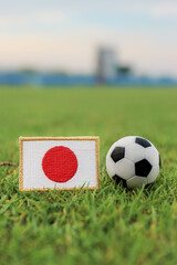 Embroidered Japan flag patch and classic soccer ball on stadium grass. Symbolic of Japanese football pride and technical precision. Ideal for world tournament news and sports marketing. © The Dell Shot by SJ