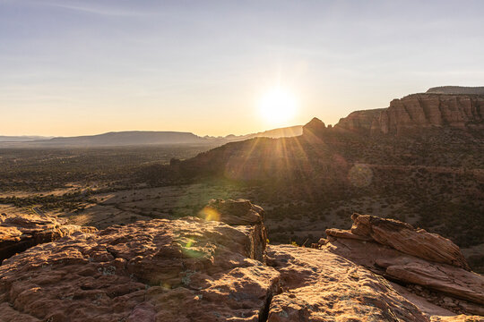 Setting sun flare over rugged rocky landscape in Sedona