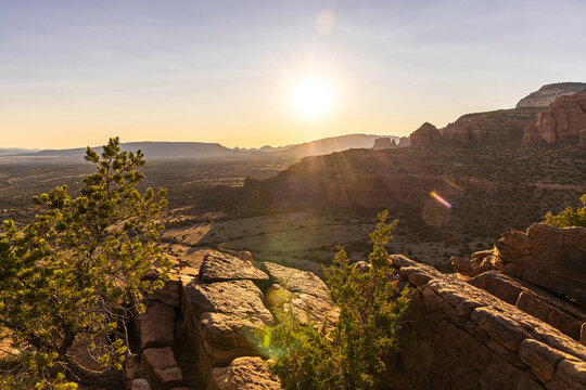 Sun setting over rugged rocky desert landscape and vegetation