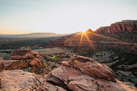 Setting sun bursts into star pattern in rocky Sedona landscape