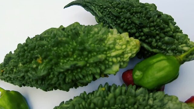 Fresh organic green bitter melon karela and spicy habanero chili peppers on white background closeup