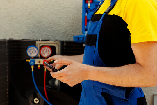 Capable electrician ordering new components for defective condenser after finishing maintenance. Meticulous wireman looking online on phone for external hvac system replacement parts, close up