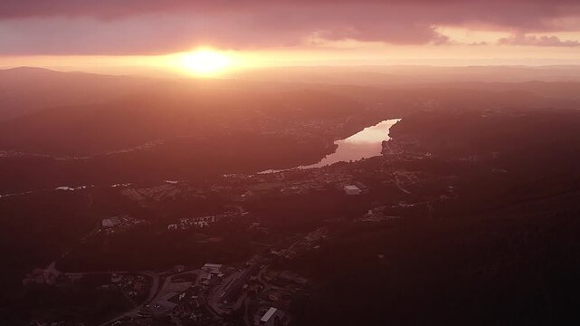 River valley in Serra da Boneca Porto district northern Portugal at sunset with golden haze over reflective water and dispersed settlements across rolling hills, aerial drone glide shot
