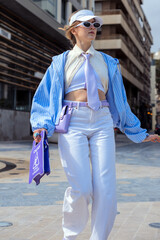 Young woman confidently walking on urban street displaying trendy purple and blue fashion style © Sunlight