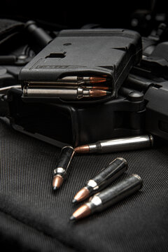 Rifle magazine and silver bullets with black tips on a dark tactical back