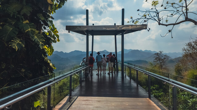 Tourists standing on mountain viewpoint platform looking at scenic landscape, Group of people enjoying panoramic view from observation deck in nature travel destination, Hellfire pass Thailand
