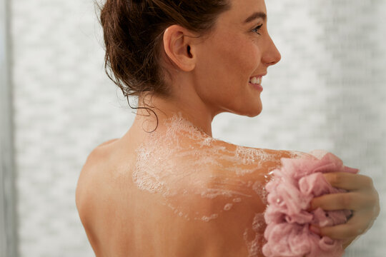 Beautiful woman showering with pink body puff