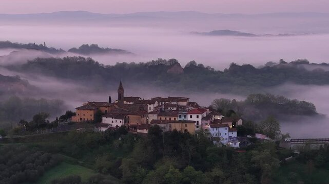 Aerial view of the historic village of Reggello surrounded by thick morning mist and rolling hills in the Tuscan countryside, Reggello, Tuscany, Italy.