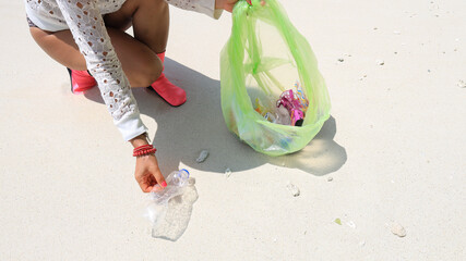 Woman volunteer which he is a pick up plastic bottle in bags that pollute sea. Problem of spilled...