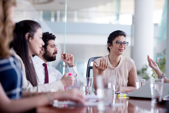 Business team meeting in modern office with diverse colleagues collaborating around conference table