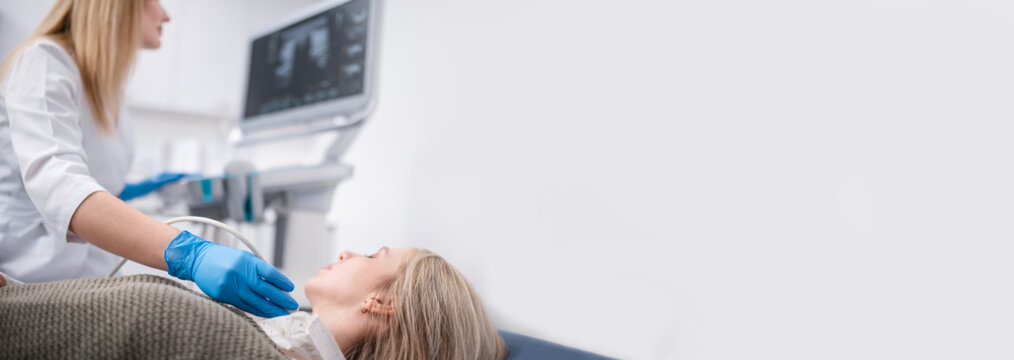 An endocrinologist examines a patient's thyroid gland using an ultrasound machine. Ultrasound machine banner copy space