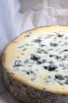 Close up shot of a slice of Fourme d'Ambert cheese in its wrapping paper.