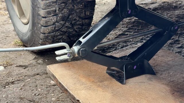 car breakdown flat tire roadside repair using scissor jack emergency wheel replacement close up