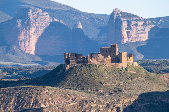 Montearagon Castle ruins on a hilltop near Huesca, Spain, medieval fortress silhouette against the Pre-Pyrenees mountains and blue sky, historic landmark in Aragon landscape at sunset.