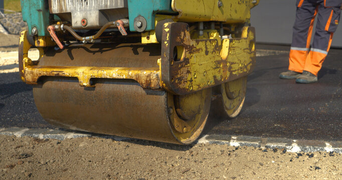CLOSE UP: Working with asphalt roller for compacting asphalt while paving yard