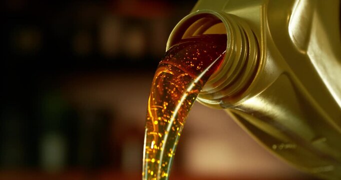 Super slow motion (1000 fps) close-up of motor oil pouring from a container. Smooth golden liquid flow with bubbles and reflections, isolated cinematic shot with shallow depth of field.