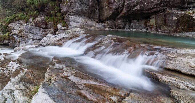 Time-lapse of mountain stream flowing over rocks in valley, captured with ND filter for smooth motion and serene natural beauty. 