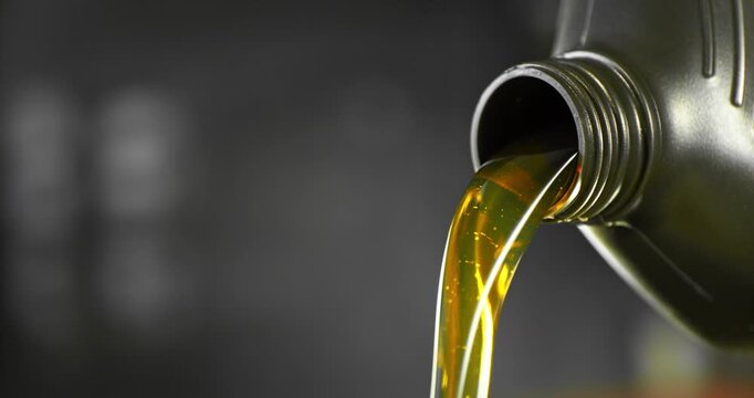 Super slow motion (1000 fps) close-up of motor oil pouring from a container. Smooth golden liquid flow with bubbles and reflections, isolated cinematic shot with shallow depth of field.