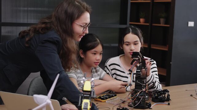 Multiracial girls learning about robotics from female teacher