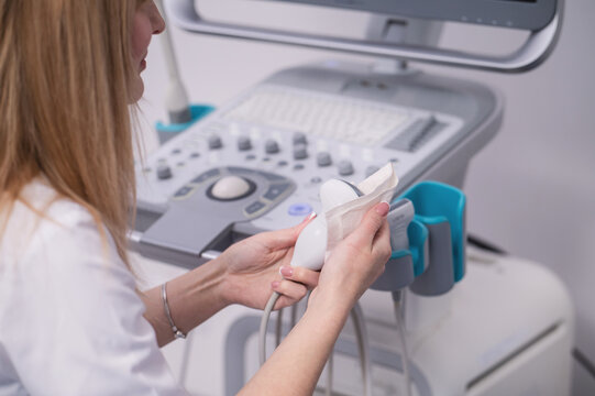 The doctor wiped the ultrasound machine sensor with an antiseptic. Safety and hygiene measures in the clinic.