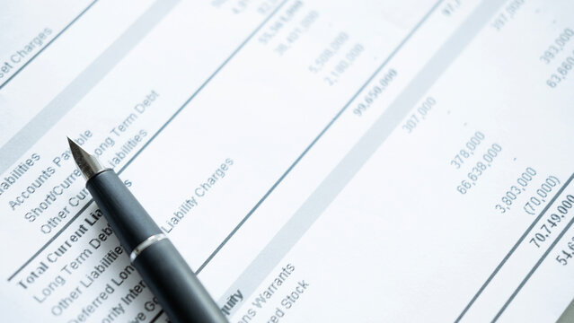 Close up of pen on liabilities section of financial statement, debt analysis, accounting review and corporate finance concept.