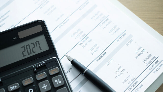 Calculator showing 2027 on financial report with pen, annual budget planning, business forecast and finance management concept.