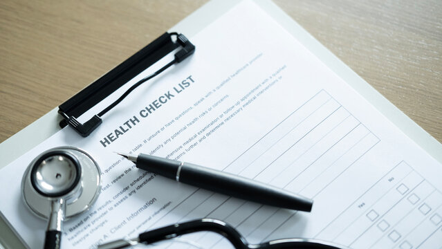 Close up of health checklist form with stethoscope, pen and eyeglasses on clipboard, medical examination and patient assessment concept.