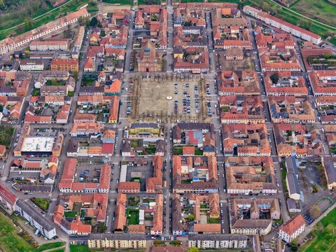 Aerial view of the octagonal fortress city, a starburst of terracotta roofs and pale stone streets, unfolds in geometric precision, Neuf-Brisach, Grand Est, France.