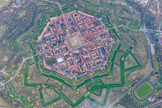 Aerial view of the star-shaped fortress with its symmetrical layout and red-roofed buildings nestled within lush green moats, Neuf-Brisach, Grand Est, France.