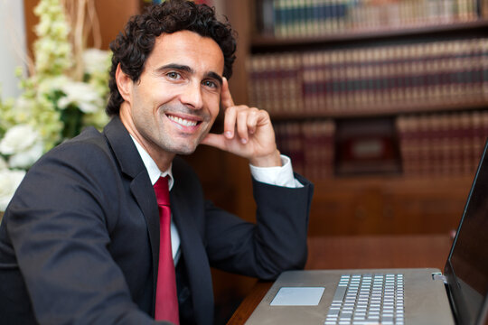 Confident businessman with laptop at desk