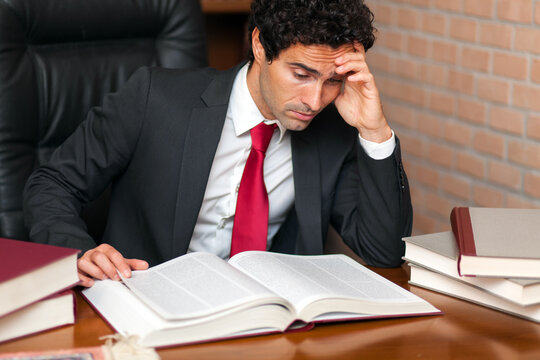 Young male entrepreneur in a suit looks stressed while studying