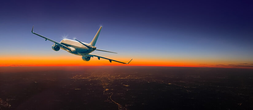 Commercial airliner flying during beautiful sunset over city lights