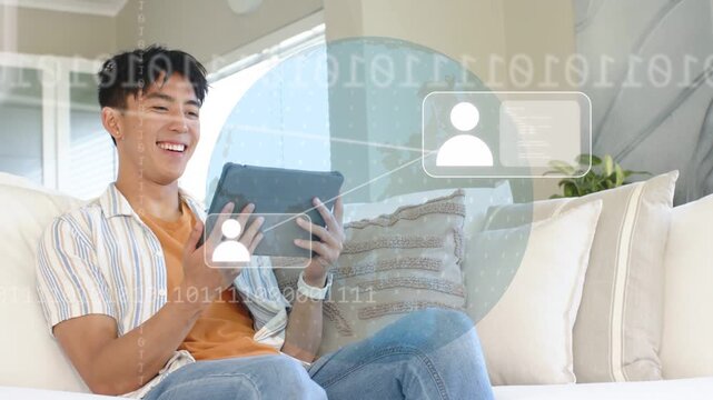 Vertical video: Man tapping tablet on sofa, forming globe, icons and binary while viewing tech map